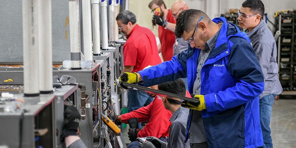 Students working on air exchange unit inside lab full of equipment.