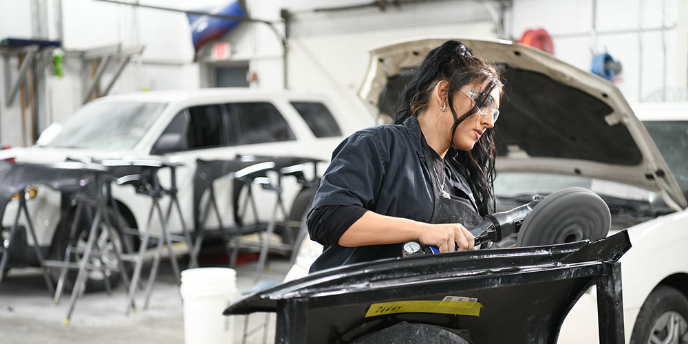 Student learning to buff a fender in the collision repair shop.