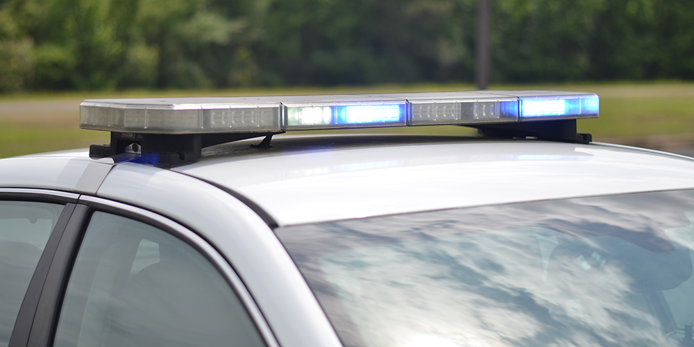 University of Arkansas System Criminal Justice Institute logo over flashing police car lights.