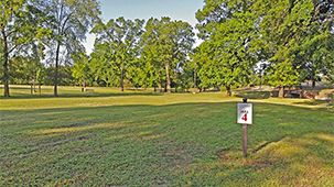 Disc golf course with hole 4 sign in foreground and bridge and holes in background.