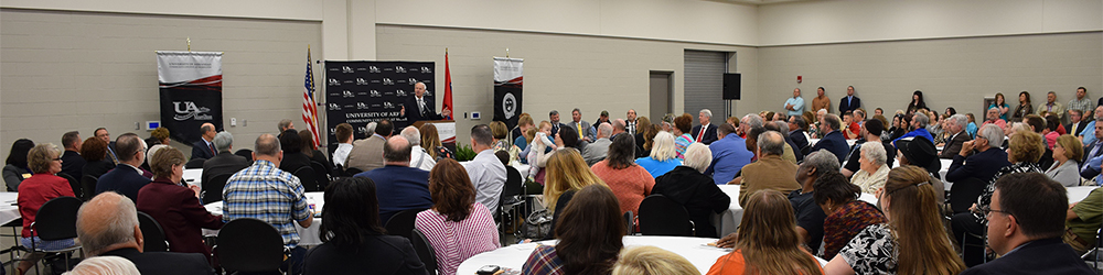 Guests in Tyson Training Hall facing speaker at the podium.