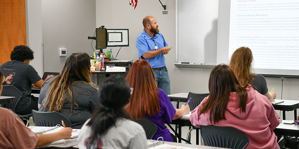 Students in class listening to instructor explain lesson.