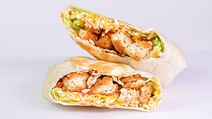 Chicken wrap cut in half showign tomato, lettuce, cheese, chicken, and carrots.