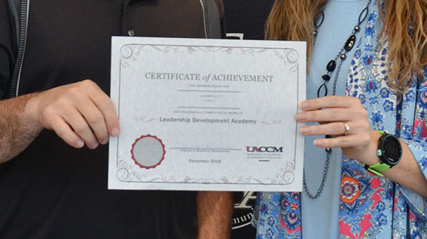 Presenter and program completer holding Certificate of Achievement.