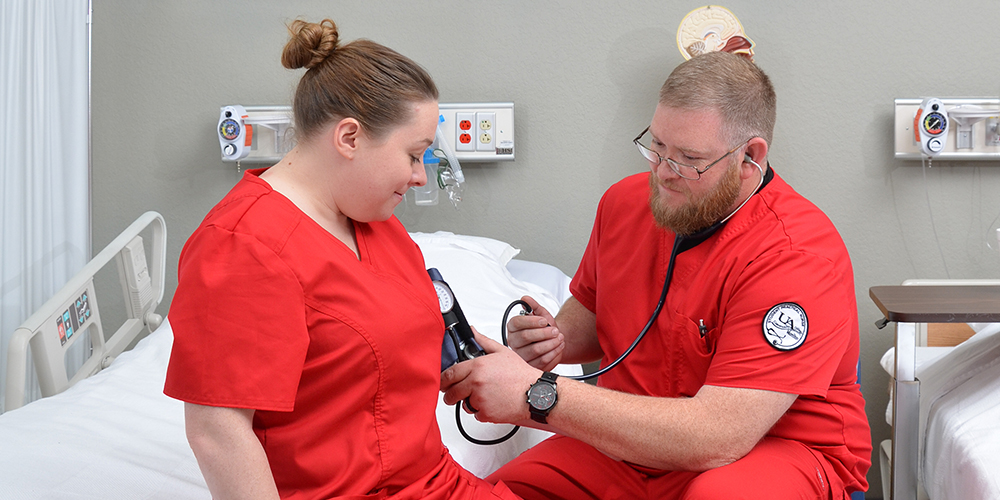 Two nursing students practicing taking blood pressure readings.
