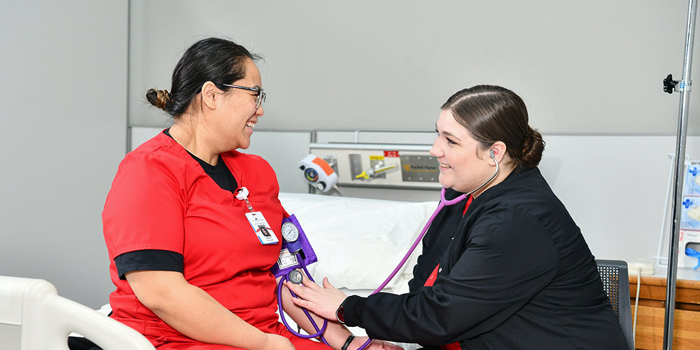 Two nursing students practicing taking blood pressure readings.