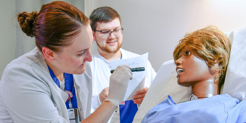 Student checks the throat of a sim-man in the Skills Lab.