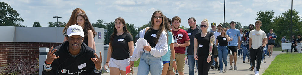 Group of new students walking down the sidewalk posing for camera.