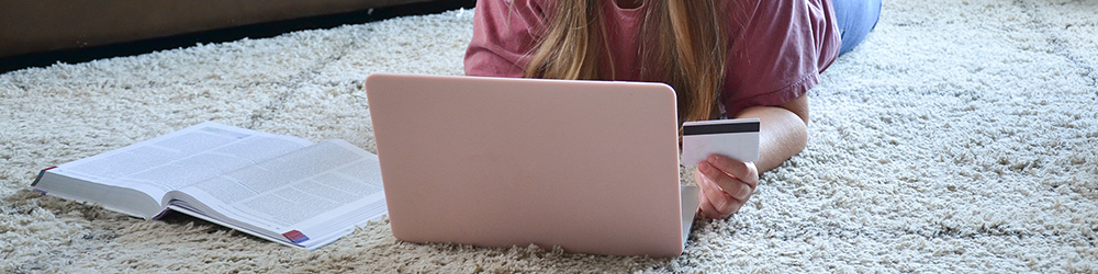 Person laying in the floor with laptop and and credit card